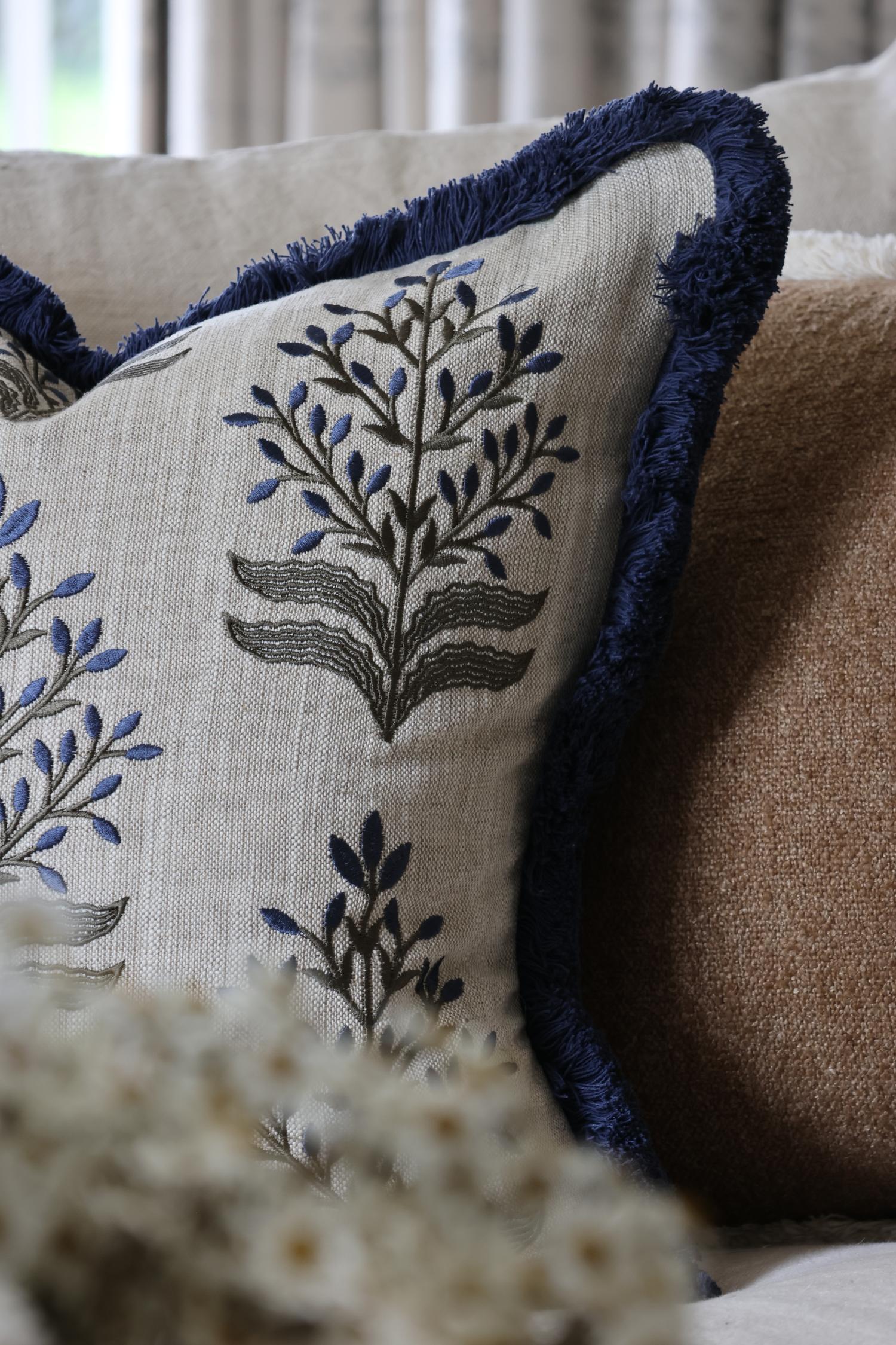 Decorative cushion with embroidered patternand fringe  on a couch