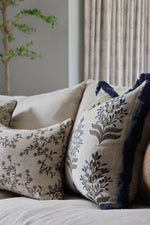 Decorative cushion with blue floral patterns on a sofa against a neutral wall.