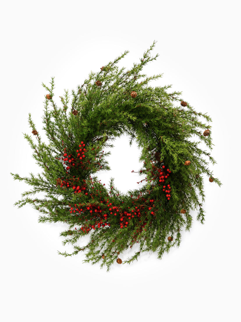A large artificial wreath with red berries on white