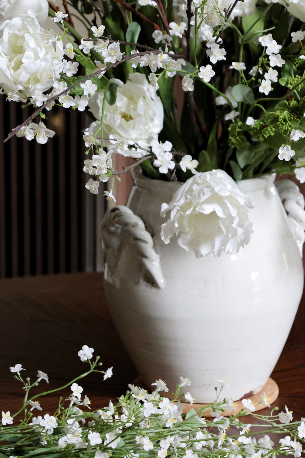 White ceramic vase with flowers on a wooden surface