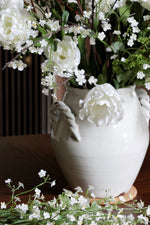 White ceramic vase with flowers on a wooden surface