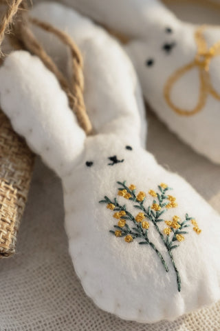 White embroidered bunny with yellow flowers on a textured surface