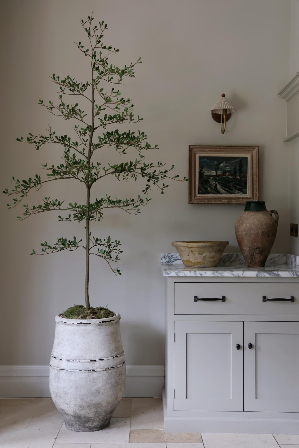 faux black olive tree in beige stone planter in a kitchen setting