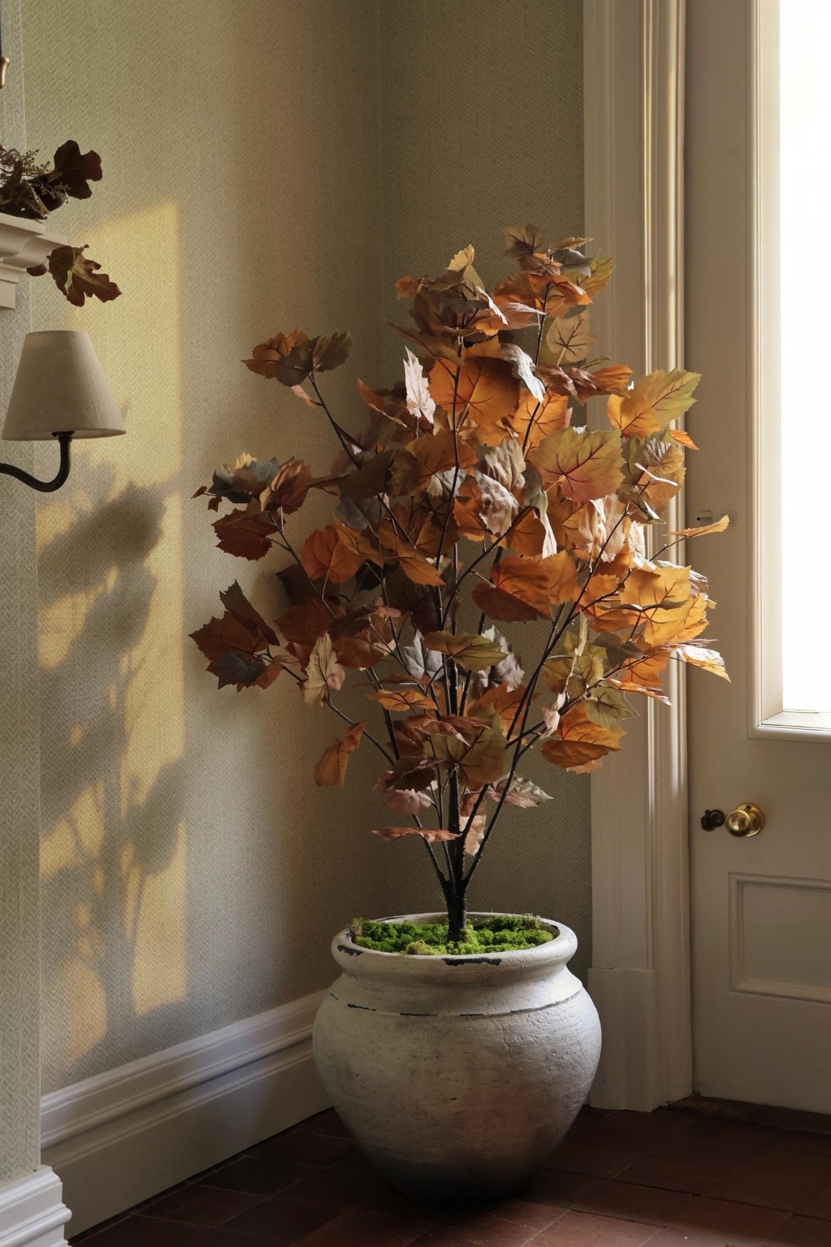 artificial autumn maple tree in cream rustic planter in corner of a room 
