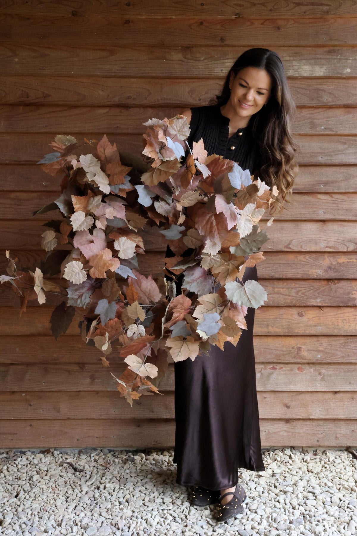 A woman holding an autumn leaves wreath