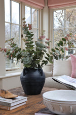 faux blush eucalyptus stems in black stone vase in garden room
