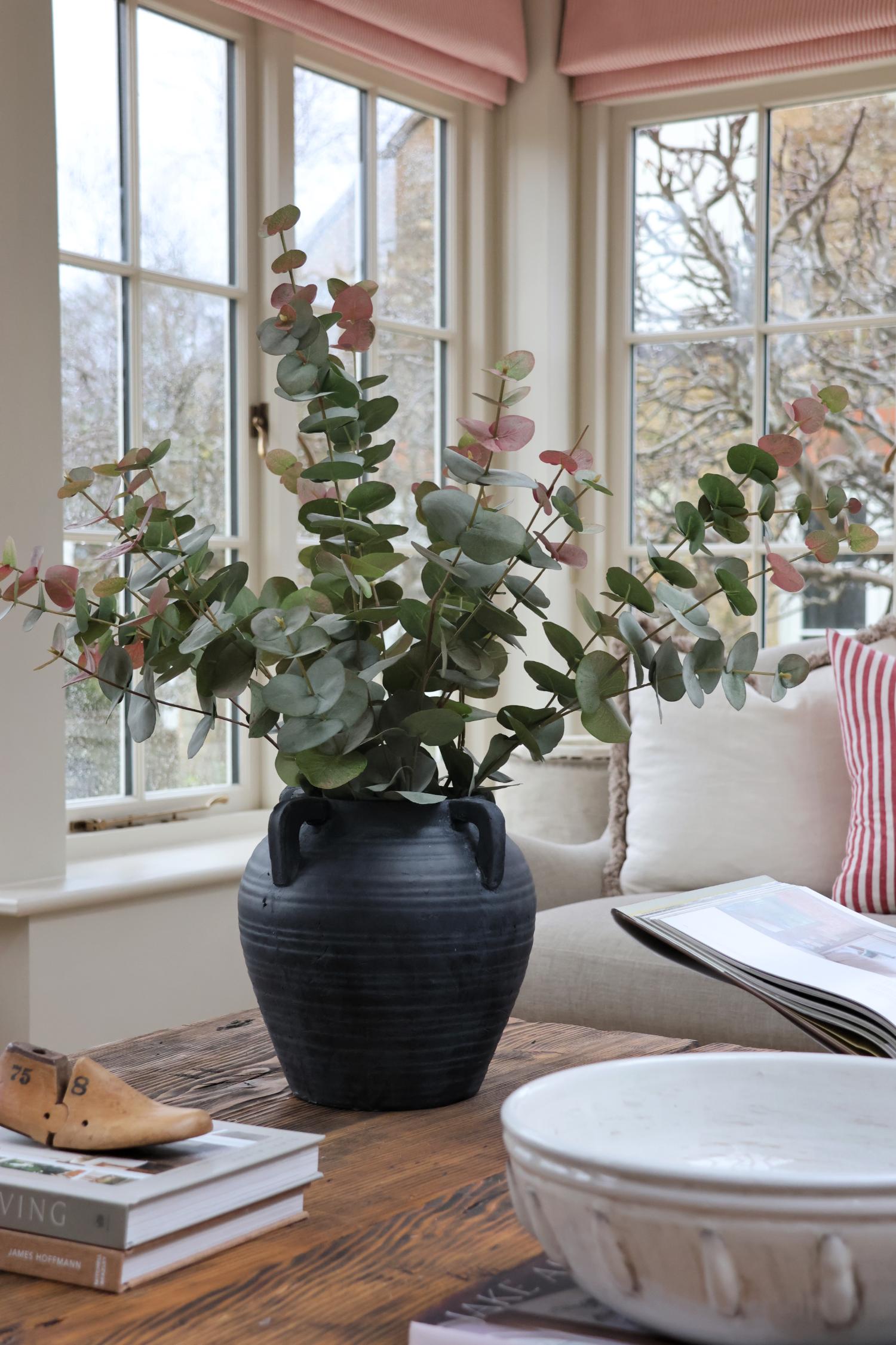 faux blush eucalyptus stems in black stone vase in garden room
