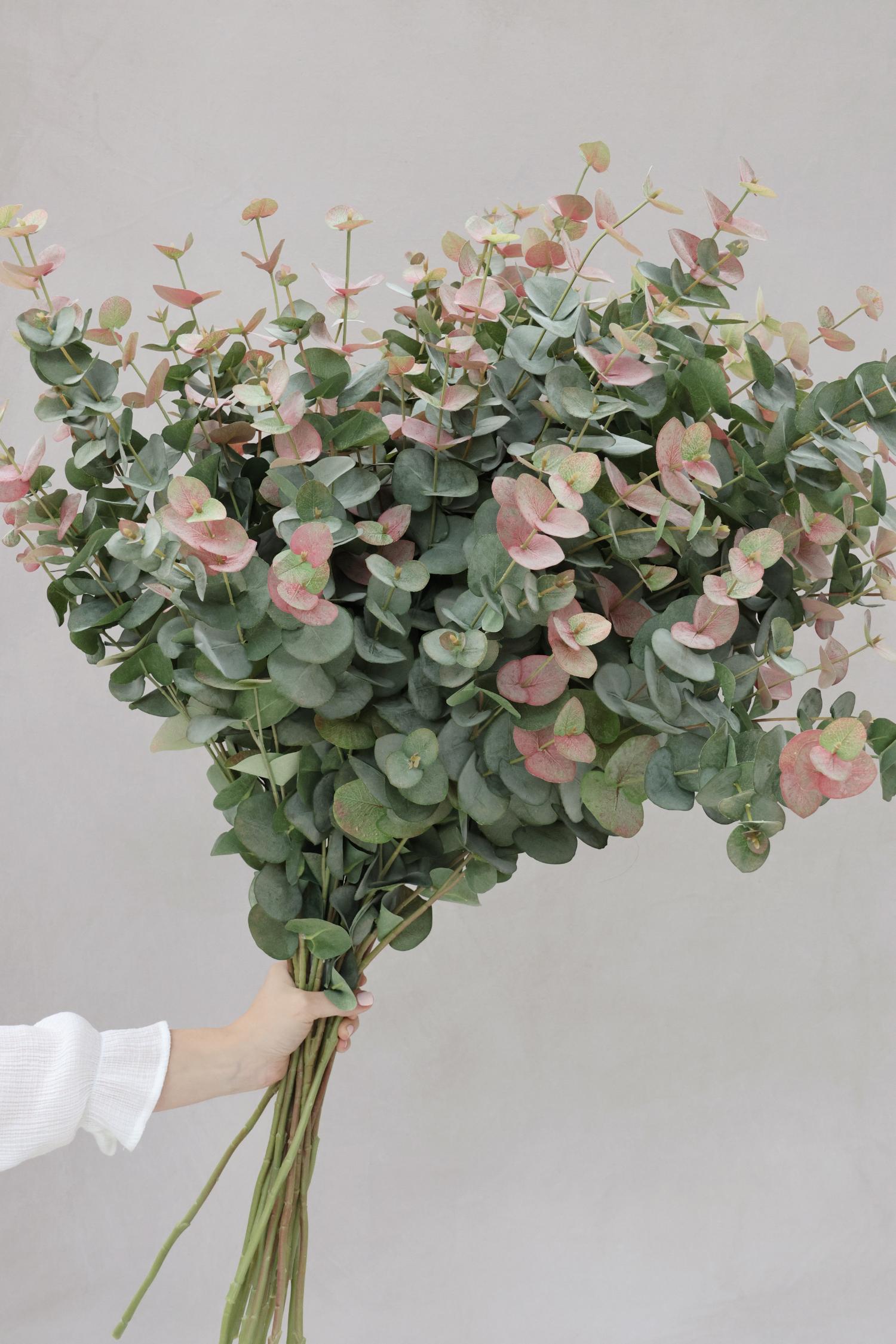 large bunch of artificial blush eucalyptus being held by womens hand