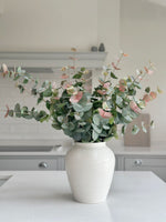 artificial pink tipped eucalyptus in white vase on kitchen island 