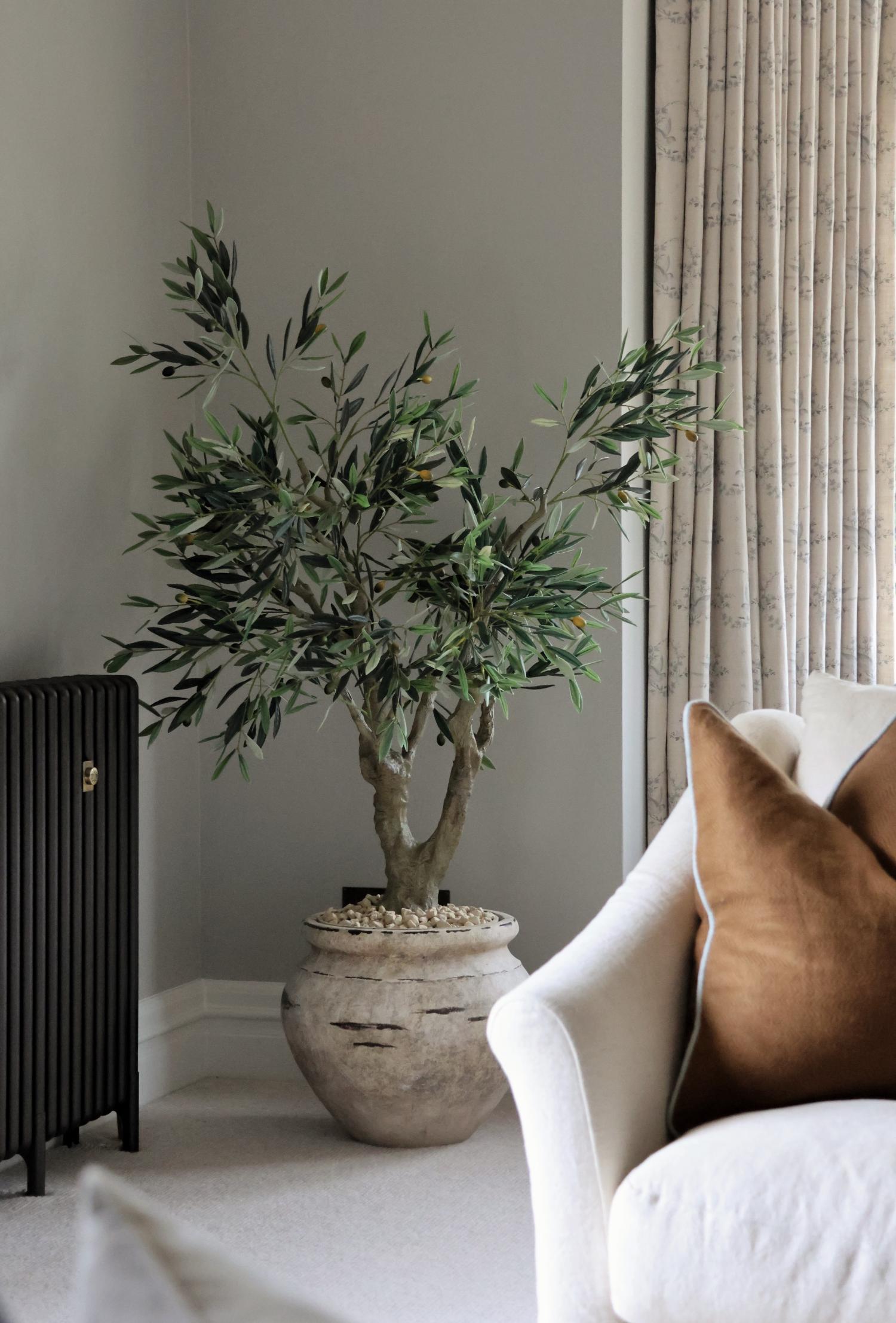 Artificial olive tree in large cream planter in a lounge setting 