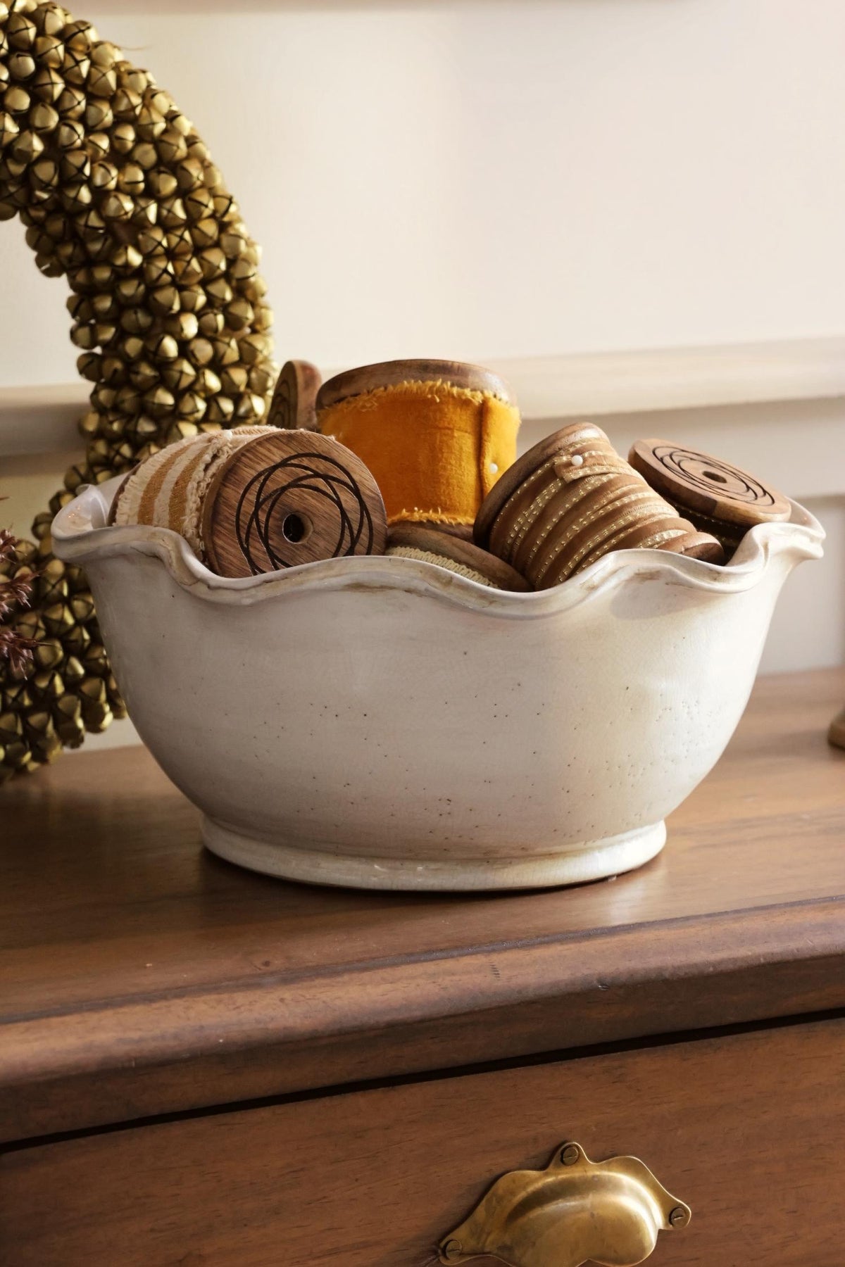 White ceramic bowl with pie crust edging filled with velvet ribbons on a wooden table 