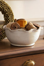 White ceramic bowl with pie crust edging filled with velvet ribbons on a wooden table 