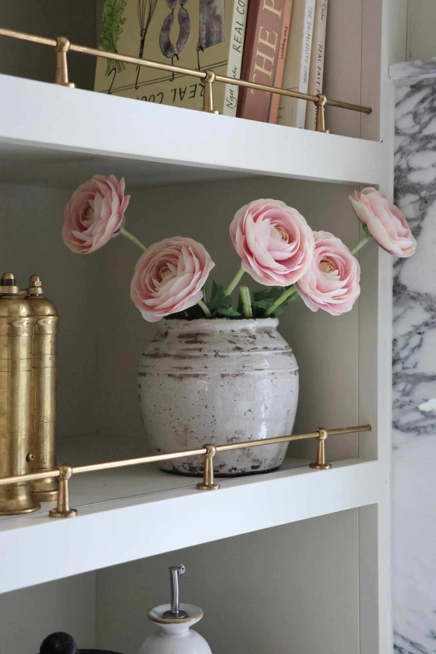 white rustic pot on shelving with faux pink ranunculus styled in it
