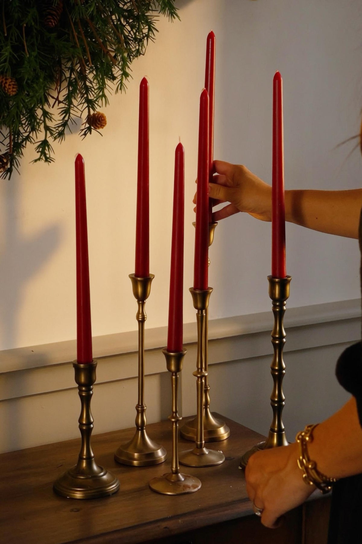 brass candlesticks with red candles on a wooden sideboard 