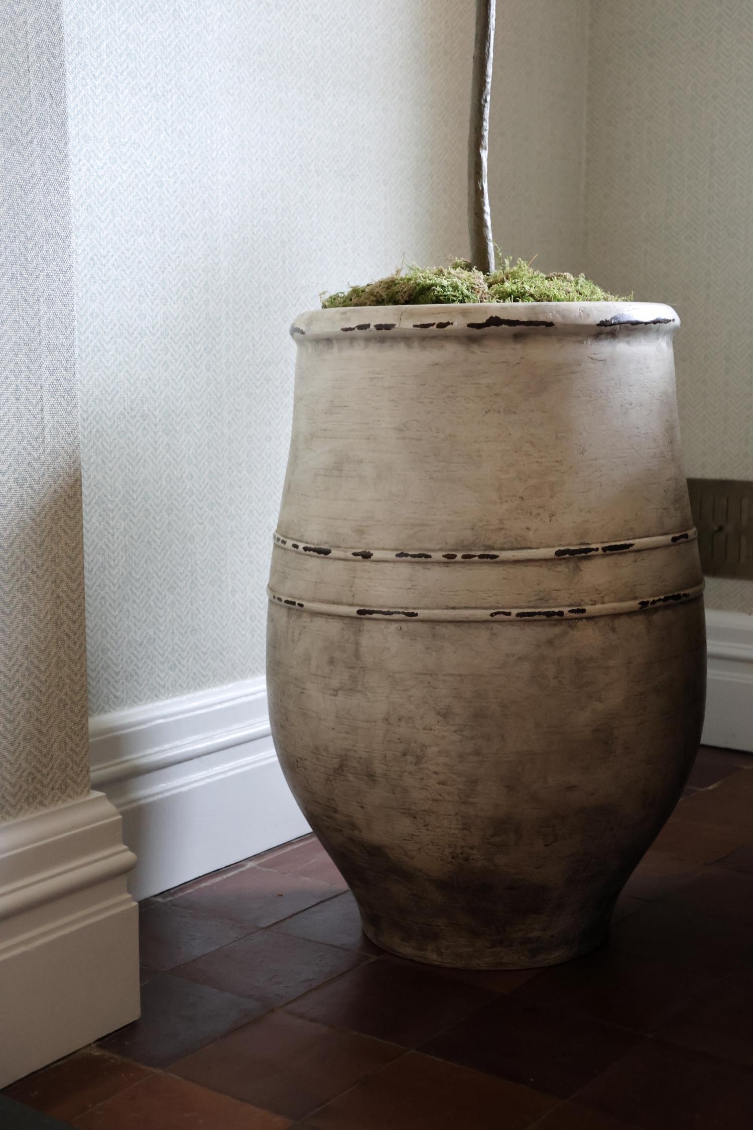 bucklesham ultra-lite planter topped with moss and a brown trunk in the corner of a home on tiles surface