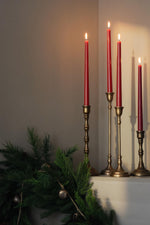 brass candlesticks with red candles on a mantel 