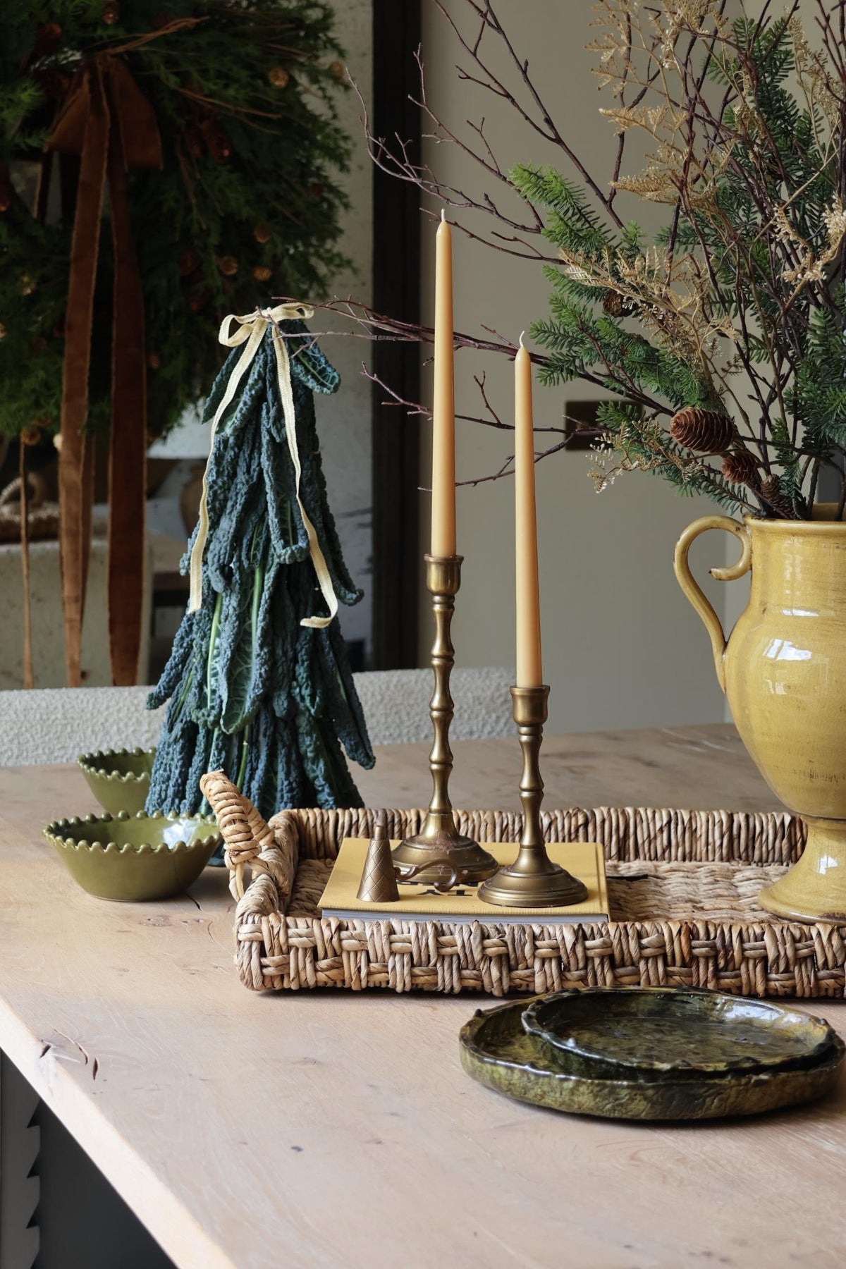 styled kitchen island for christmas with festive foliage, brass candlesticks and wreath in the background 