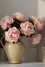 artificial Pink peony flowers in a beige jug on a neutral background
