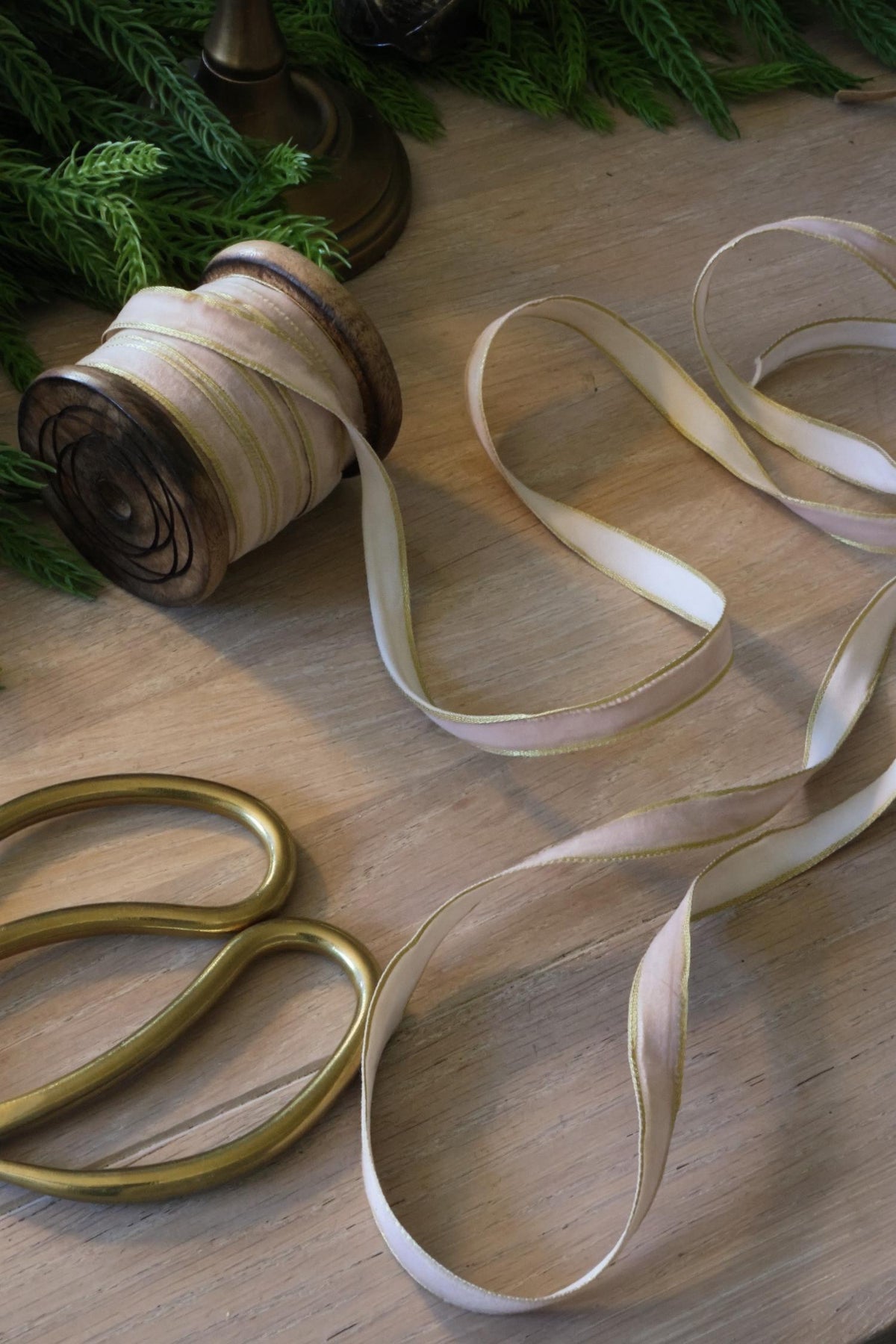 thin pale pink and gold ribbon on wooden spool with gold scissors 