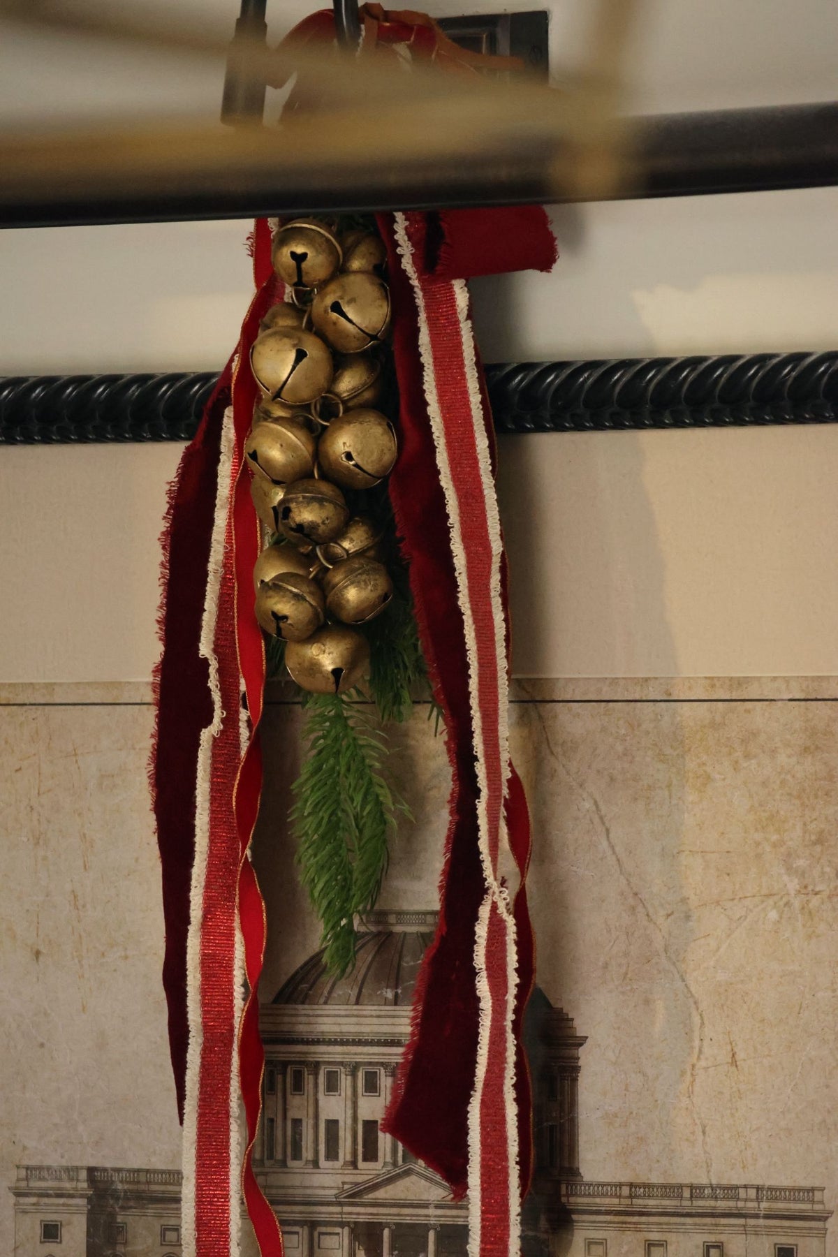 cluster of brass bells and red ribbons hanging from a picture fram 