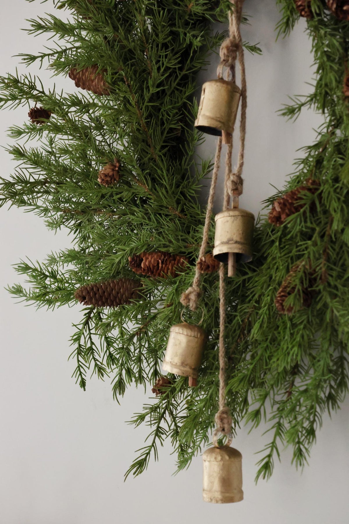String of hanging brass cowbells hanging on an artificial larix wreath 
