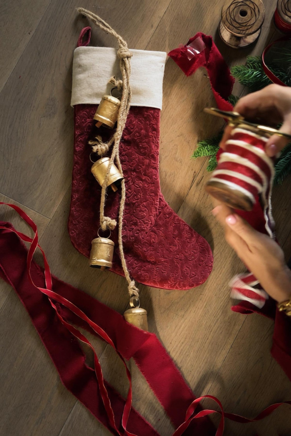 red velvet stocking with brass cowbells and red ribbon on a wooden surface 