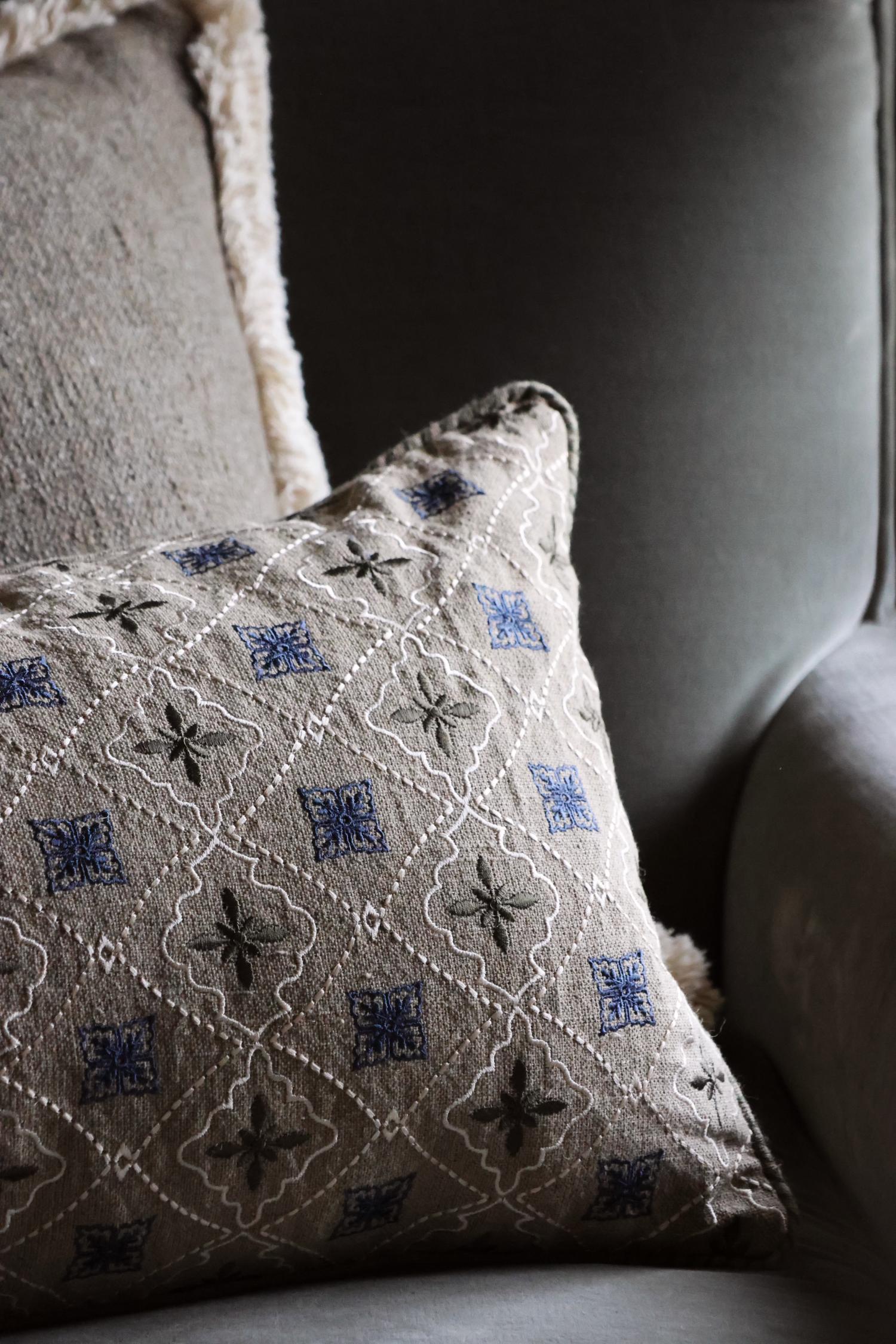 Decorative cushion with intricate patterns on a gray sofa