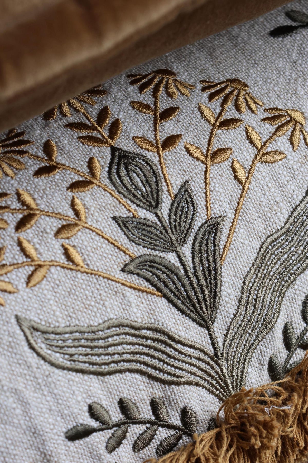 Close-up of embroidered floral design on fabric with brown and green colors.