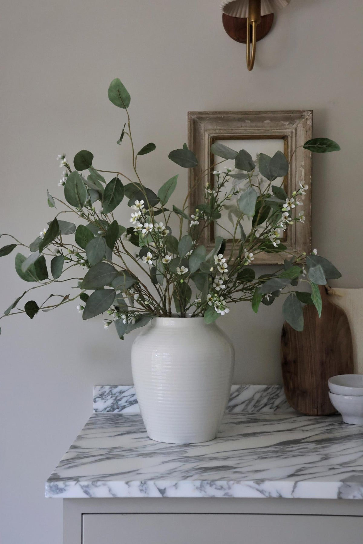 eucalyptus populus with waxflower in white vase on marble kitchen surface