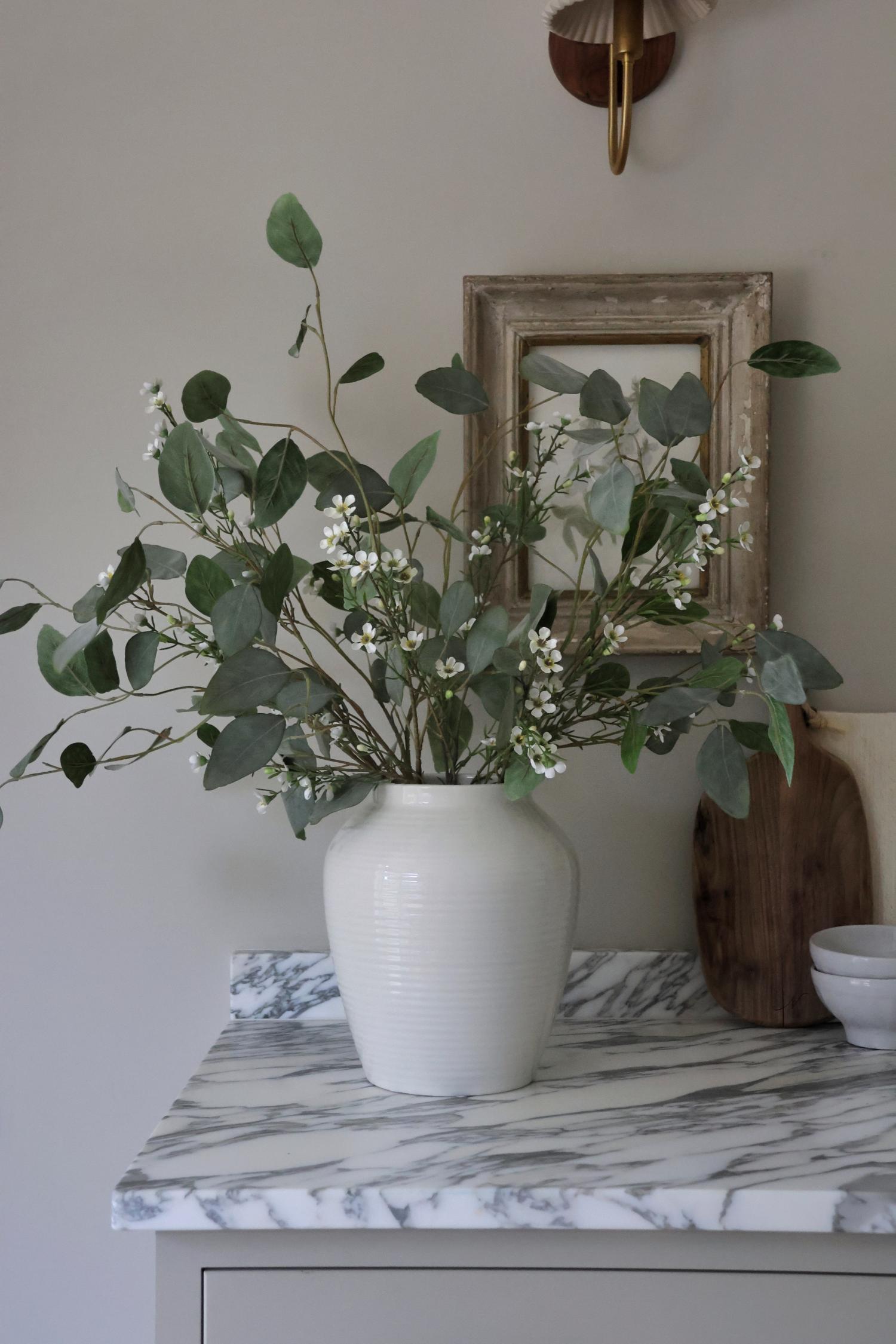 eucalyptus populus with waxflower in white vase on marble kitchen surface