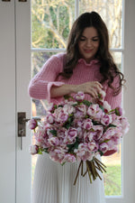 lady in pink jumper holding a large bouquet of faux blush pink peonies 