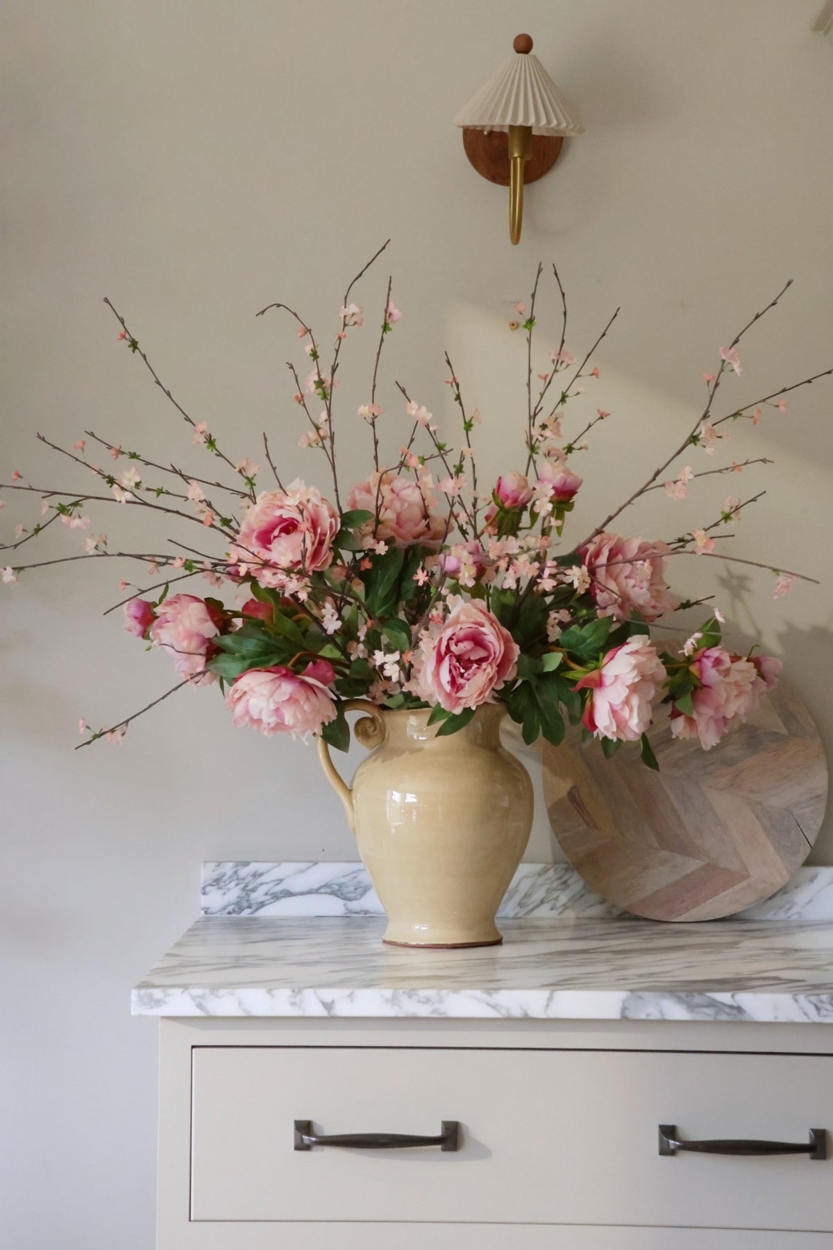 Floral arrangement in a beige vase on a marble surface with a neutral background
