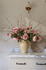 Floral arrangement in a beige vase on a marble surface with a neutral background
