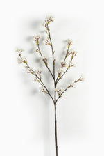 Artificial cherry blossom branch with white flowers on a white background