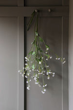 Floral faux forget me not stems hanging on a wooden panel