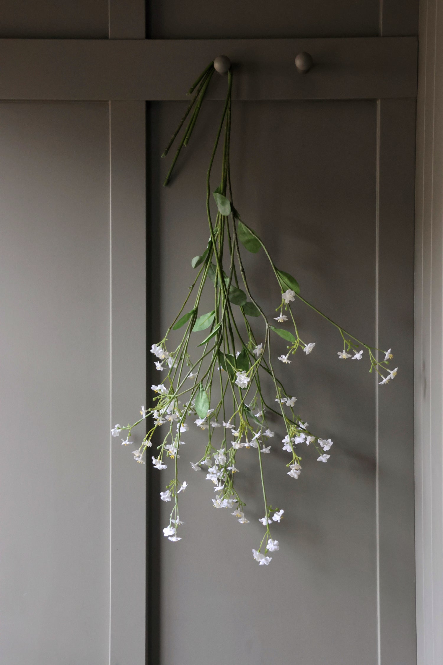Floral faux forget me not stems hanging on a wooden panel