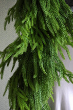 Close-up of a faux norfolk pine garland against a neutral background