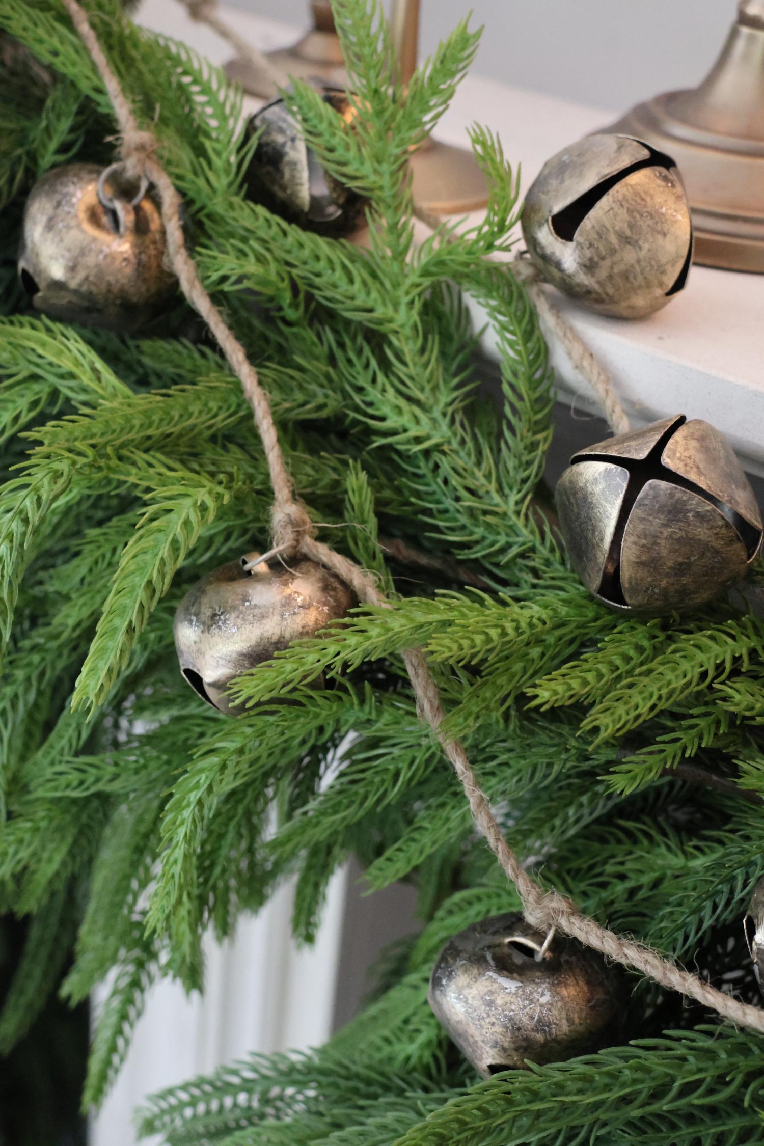 Decorative string of metallic bells hanging on an artificial norfolk pine garland 