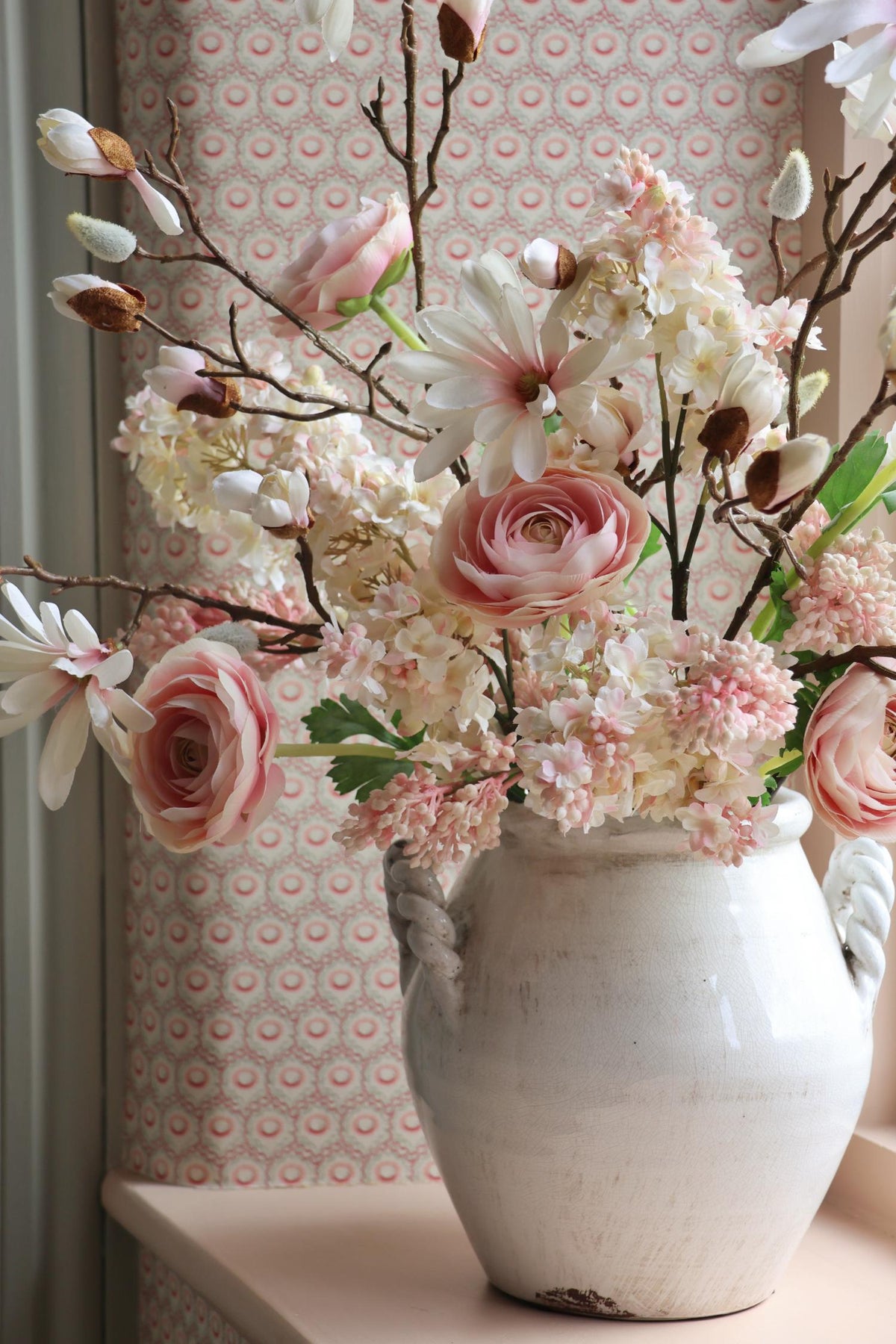 white vase on windowsill with pale pink flowers 