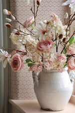 white vase on windowsill with pale pink flowers 