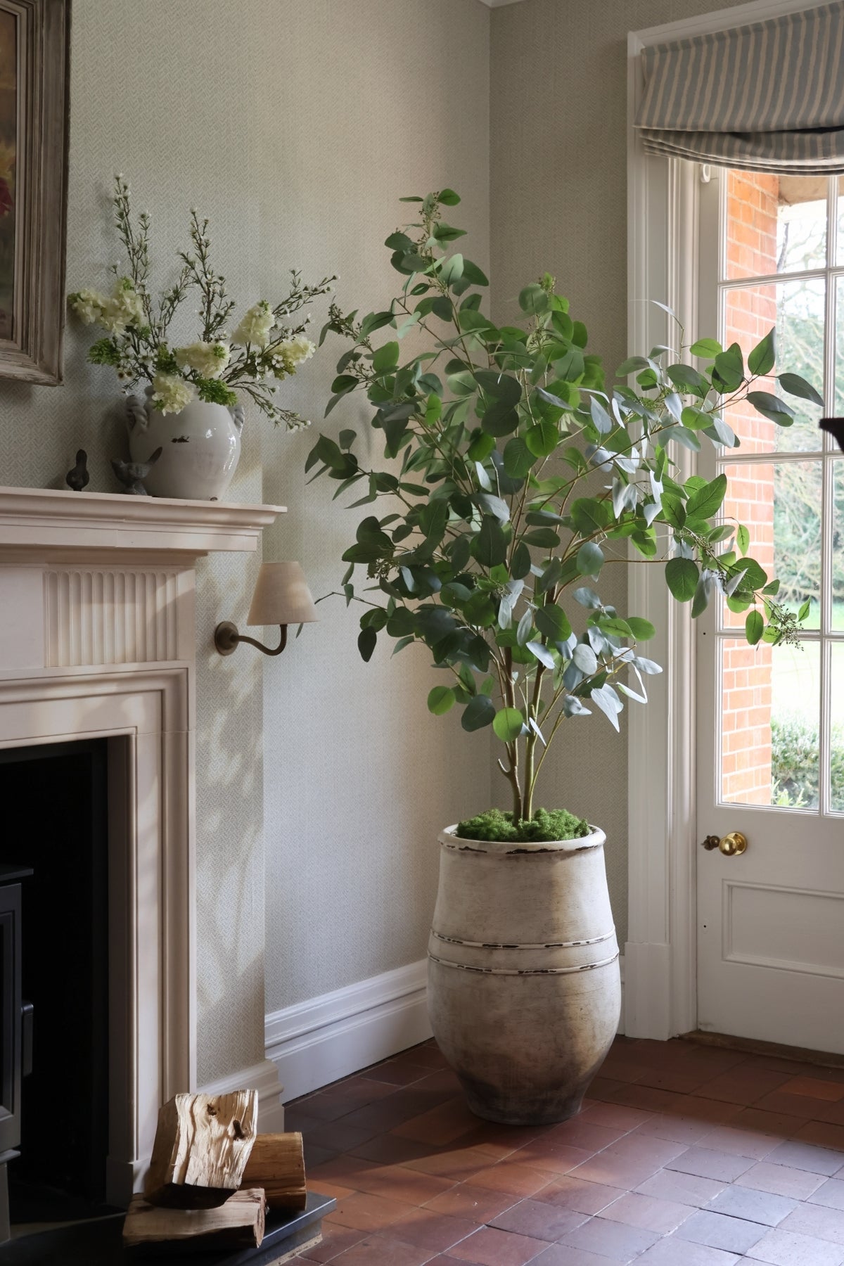 Faux Seeded Eucalyptus Tree in an Ultra-Lite planter with faux carpet moss, styled next to a fireplace