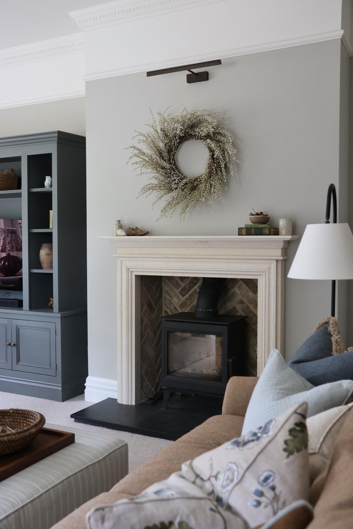 faux white willow wreath hanging above grand fireplace in cosy living room