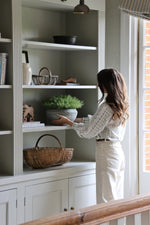 fax potted spanish moss styled on light grey cabinetry with women positioning it into place 