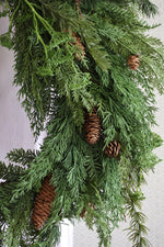 artificial foliage wreath with pinecones on a white background