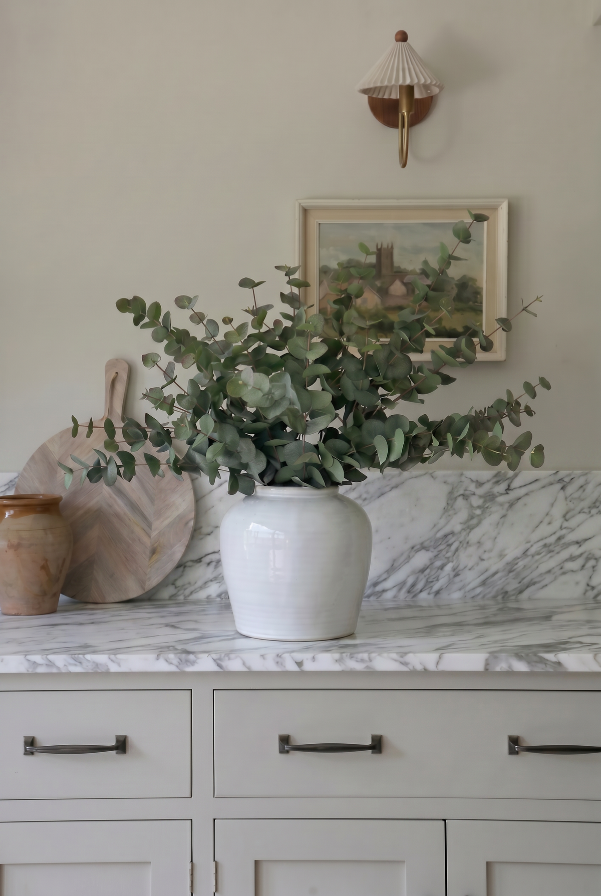 white vase with green eucalyptus on a marble kitchen worktop with splashback 
