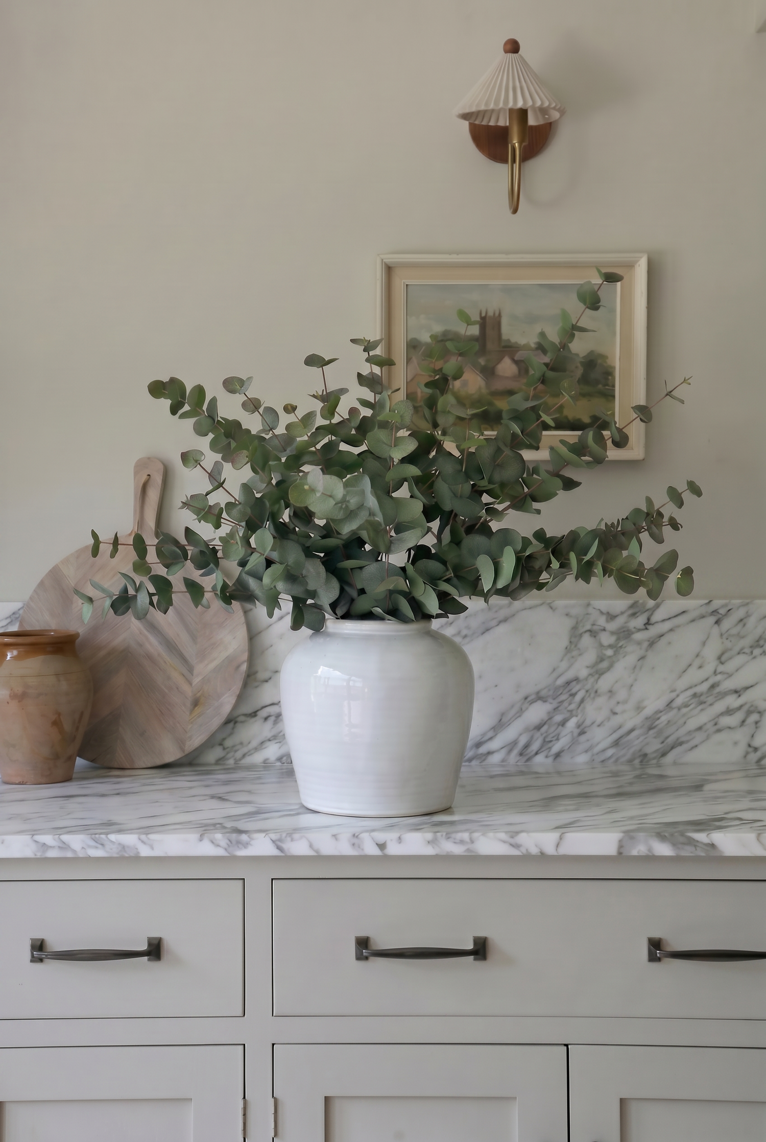 white vase with green eucalyptus on a marble kitchen worktop with splashback 