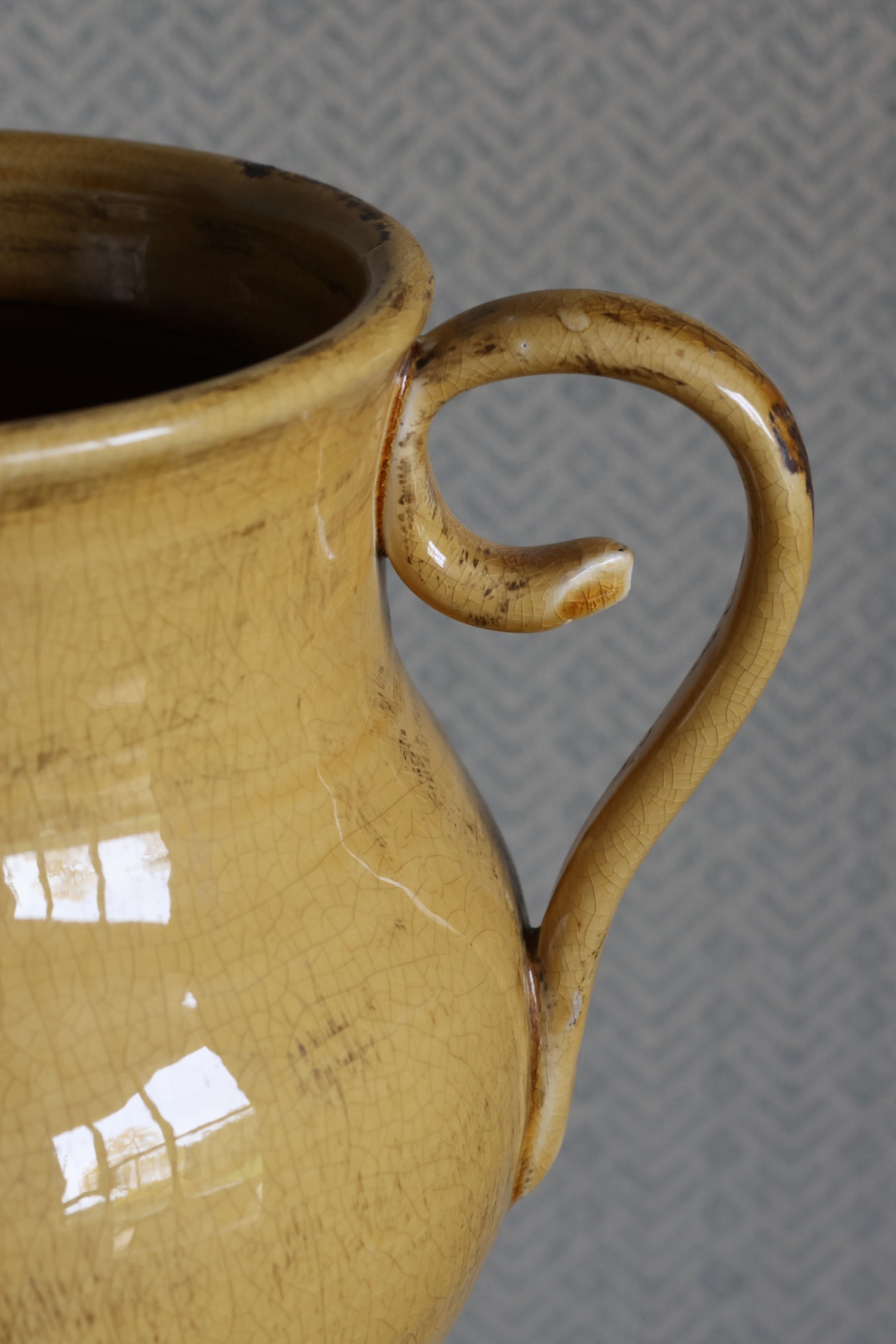 Close-up of a ceramic urn vase with a handle on a textured gray background
