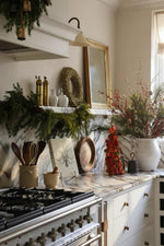 a kitchen christmas decor scene with garlands, red berry arrangements, bell wreaths 