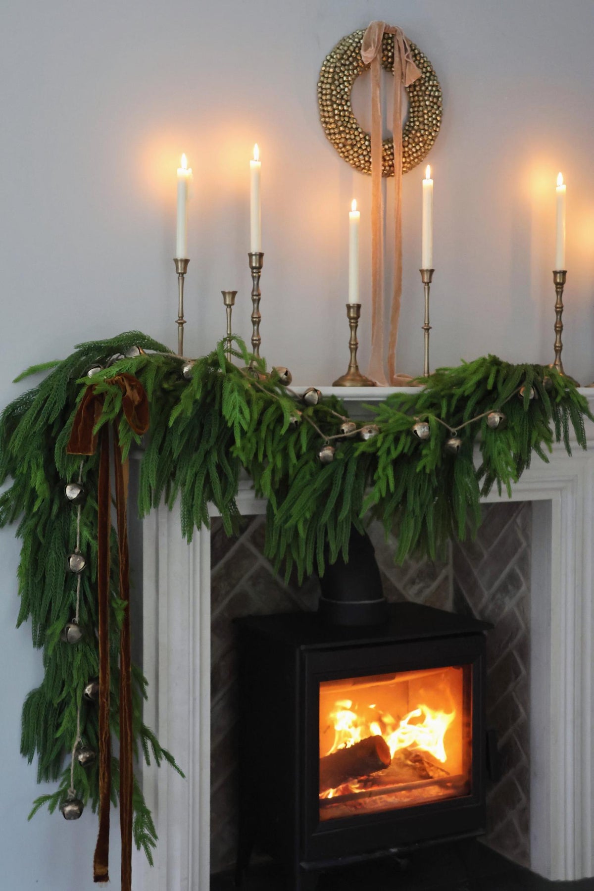 Decorative fireplace mantel with greenery, candles, and a wreath above.