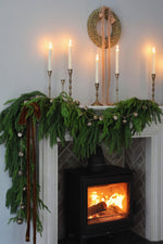 Decorative fireplace mantel with greenery, candles, and a wreath above.
